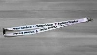 Purple lanyard with Proud Feminist = Change Maker Systems Breaker in black letters